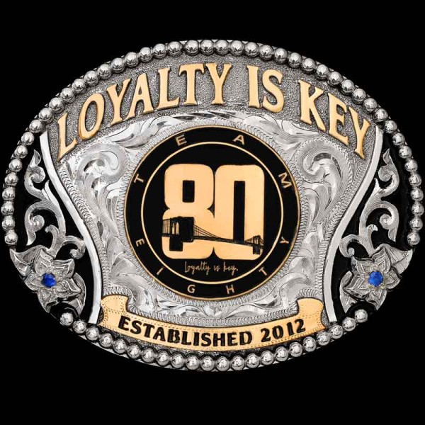 "Our San Saba Buckle is makes a beautiful keepsake to display any company logo on. This buckle is crafted on a hand-engraved, German Silver base. It is detailed with a beaded edge, beautiful German Silver scrolls, flowers and Jeweler's Bronze letteri